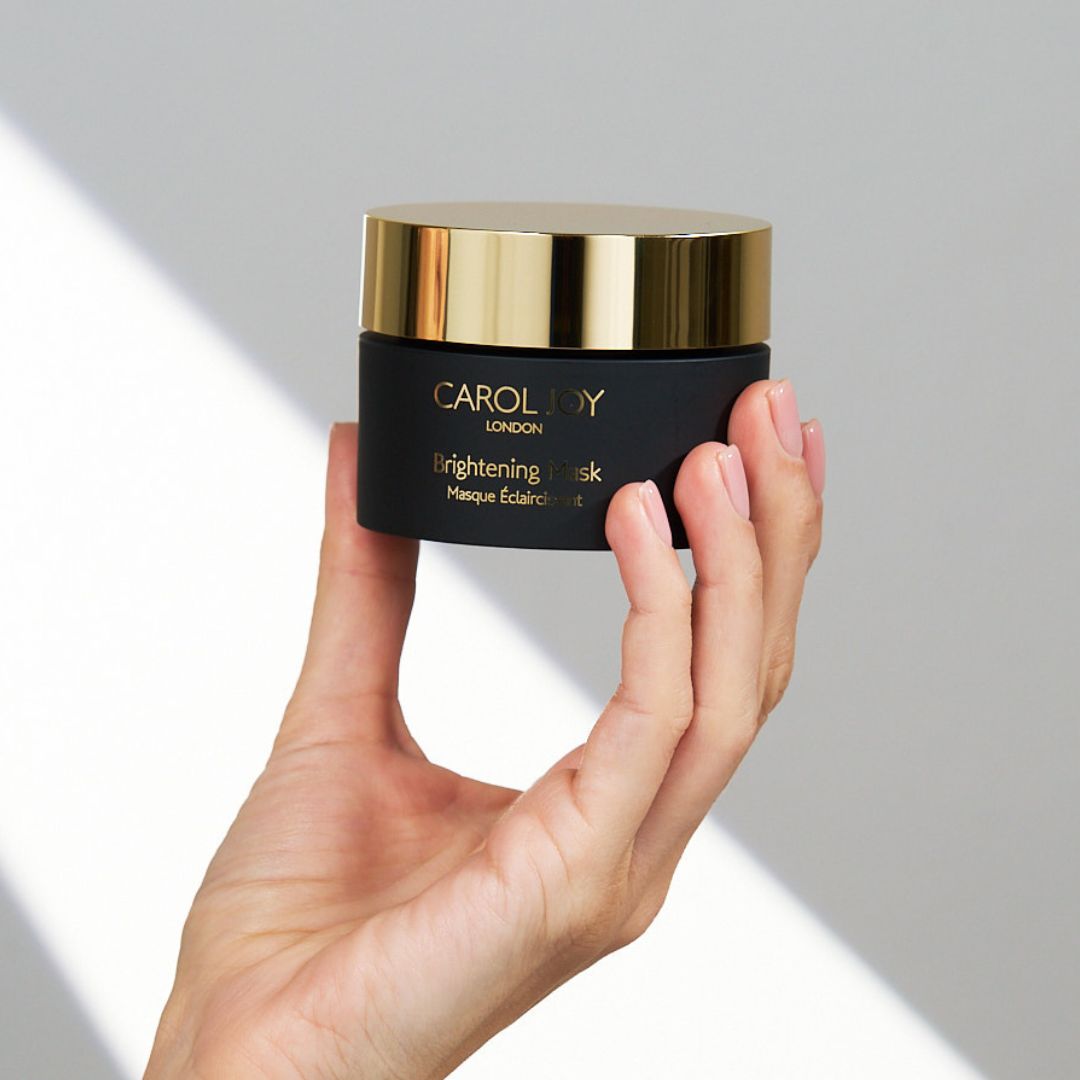 Hand holding the Carol Joy London Brightening Mask against a plain white background