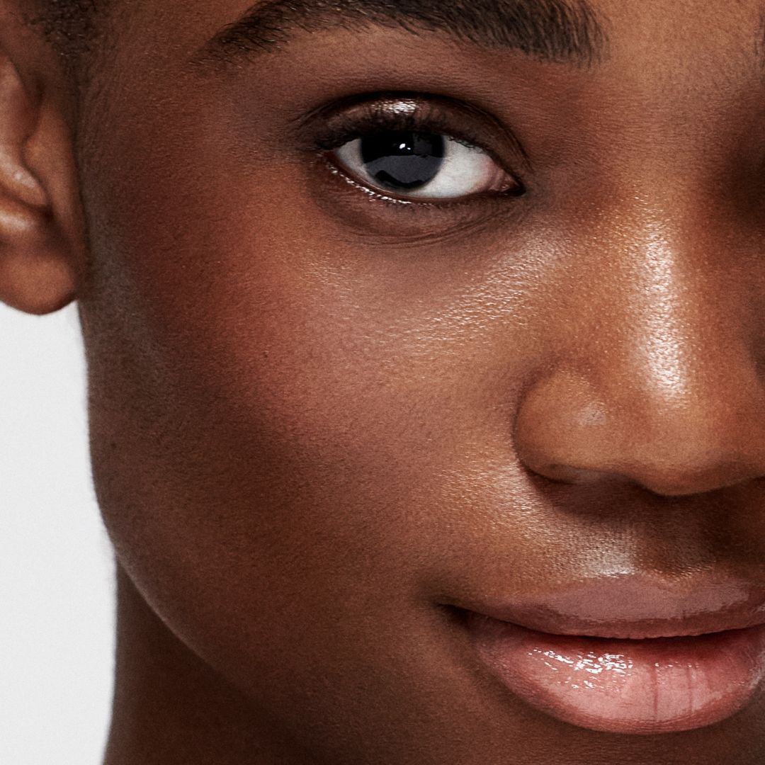Close-up of barefaced model with clear skin smiling